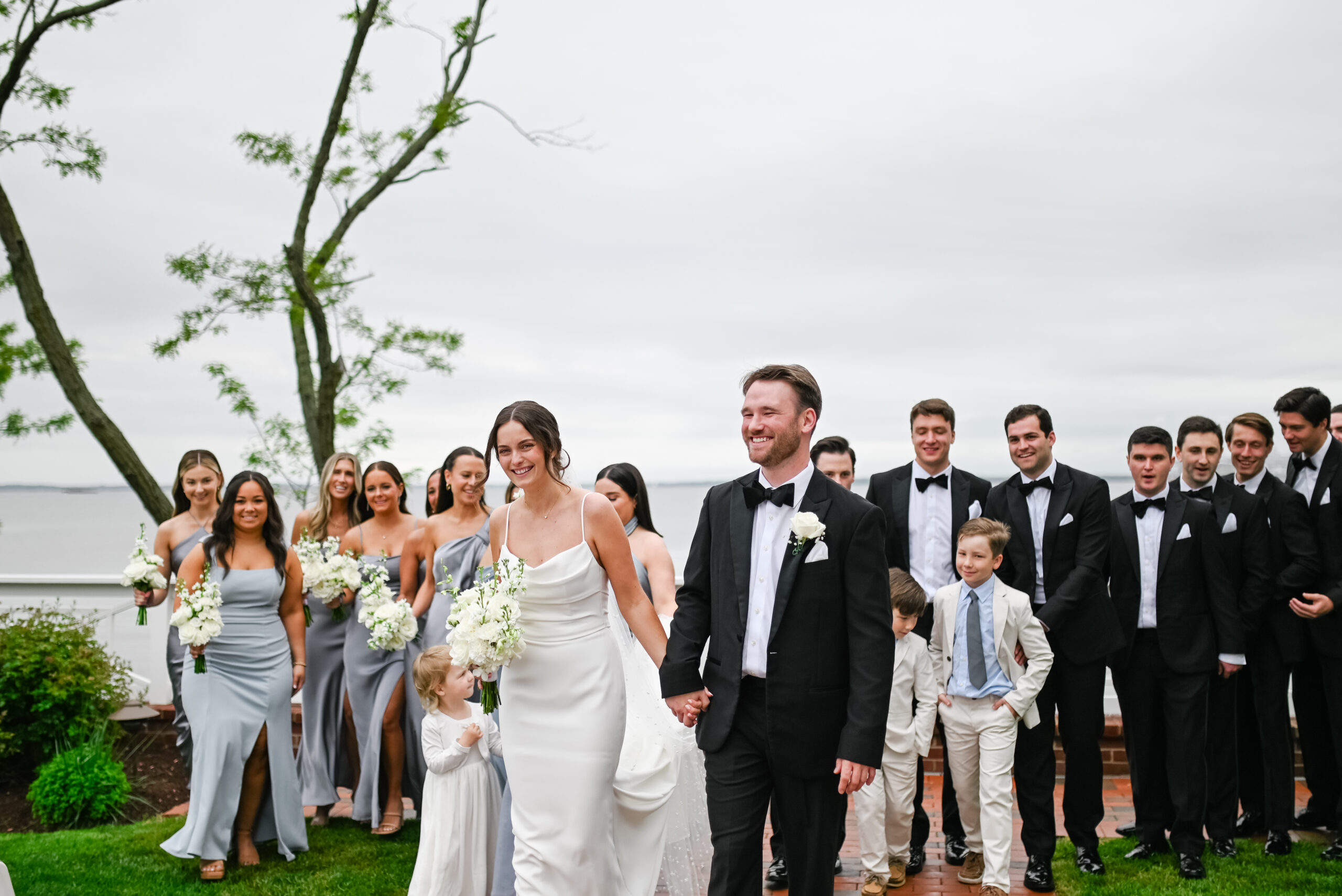 couples walks with bridal party by Chesapeake Bay